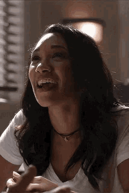 a woman is laughing while sitting at a table with her mouth open .
