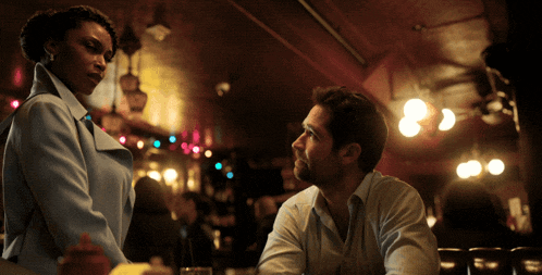 a man and a woman are sitting at a table in a dark room