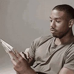 a man in a gray shirt is reading a book