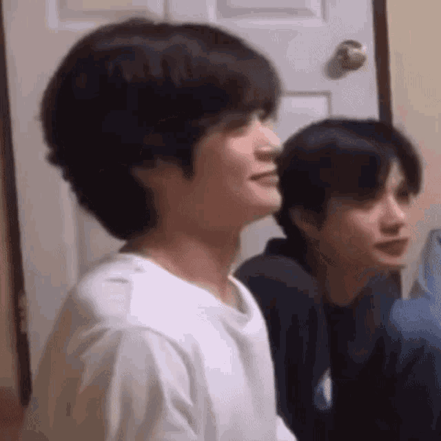 a group of young men are sitting in front of a door .