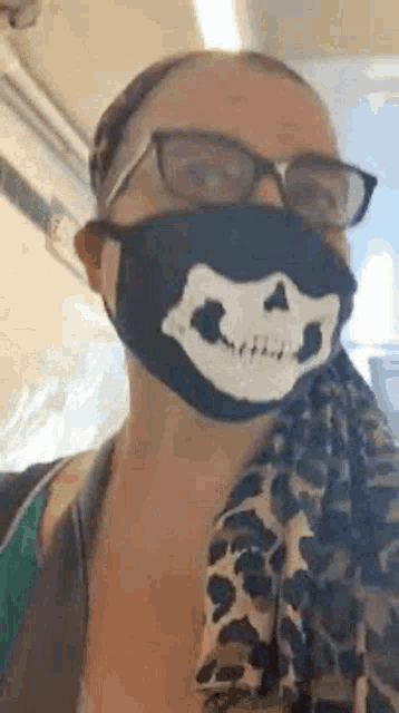 a woman wearing a face mask with a skull on it and glasses .