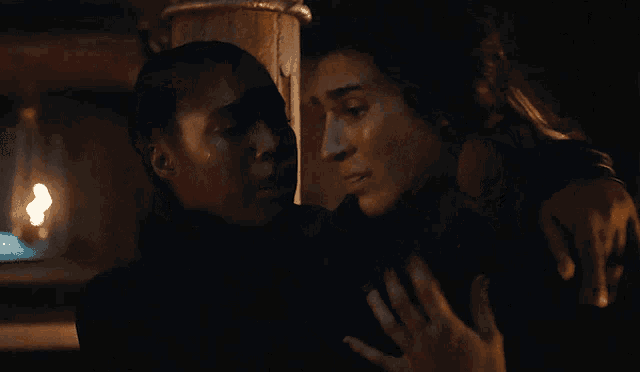 two women are hugging each other in the dark and one of them is crying
