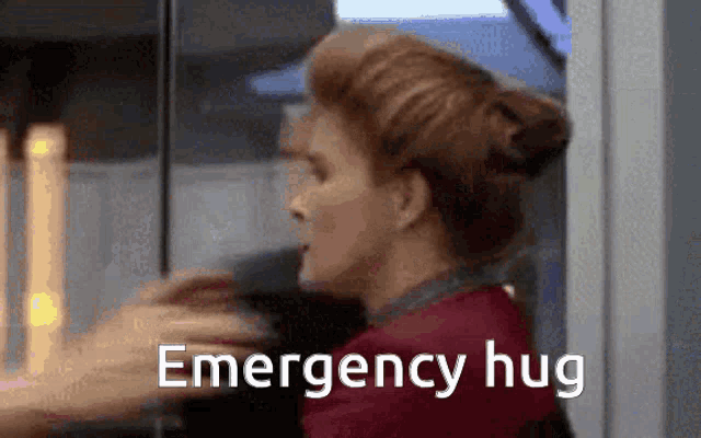 a woman is hugging another woman with the words `` emergency hug '' written on the bottom of the image .
