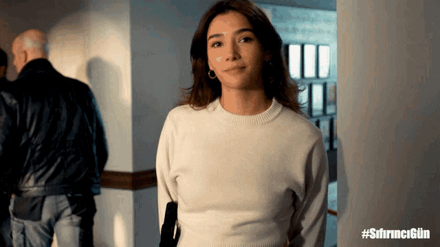 a woman in a white sweater is standing in a hallway with the hashtag #sfirncgün