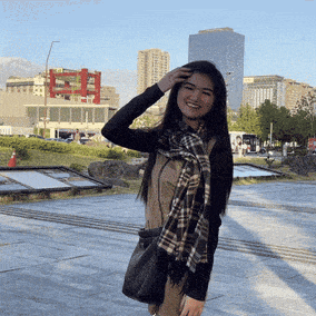 a woman wearing a plaid scarf stands in front of a building that says eh on it