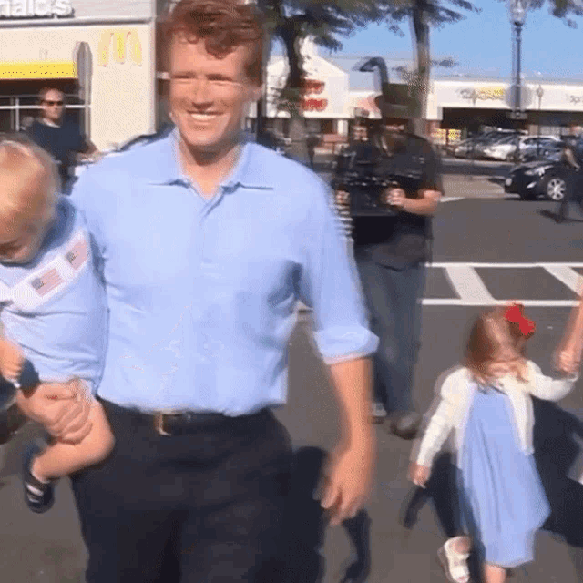 a man in a blue shirt is holding a baby in his arms