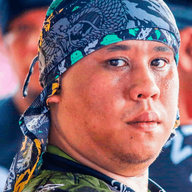a close up of a man wearing a headband with a dragon on it