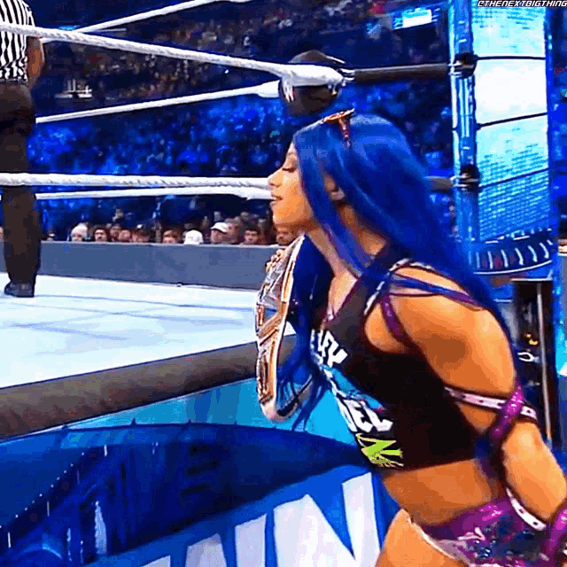 a woman with blue hair is holding a wrestling championship belt in a ring