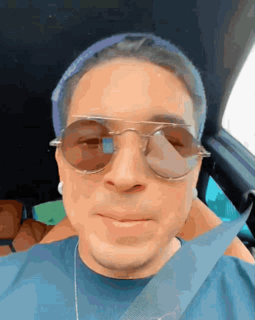 a man wearing sunglasses and a blue hat is smiling in a car