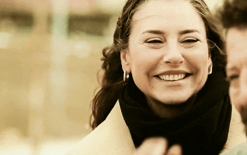 a woman wearing hoop earrings and a scarf smiles at the camera