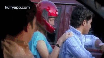 a man and a woman are riding in a car and the woman is wearing a helmet .