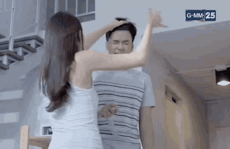 a woman is holding a man 's head while standing next to him in a room .