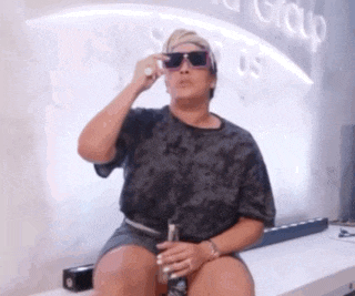 a woman wearing sunglasses is sitting in front of a sign that says so group