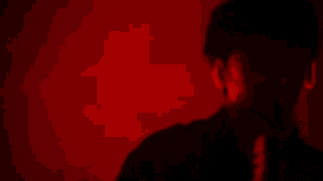 a man is singing into a microphone in a red background