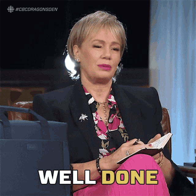 a woman is sitting in a chair and holding a notebook and the words well done are above her