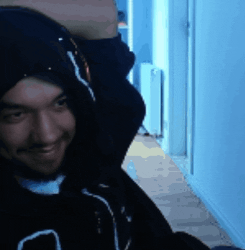 a man wearing a black hoodie with the letter a on it smiles