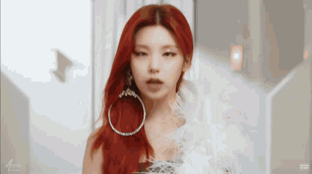 a woman with red hair and hoop earrings is wearing a white feather boa around her neck .
