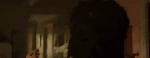 a man and a woman are standing next to each other in a dark room and looking at each other .