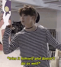 a man in a striped shirt is standing in a room and says tries it himself and does n't