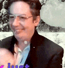 a man wearing glasses and a suit is smiling and holding a baby .