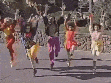 a group of people are jumping in the air while dancing on the street .