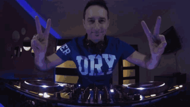 a man wearing a blue shirt with the word dry on it is giving a peace sign