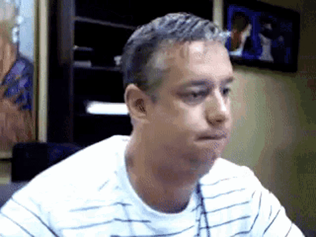 a man in a striped shirt is sitting in front of a tv