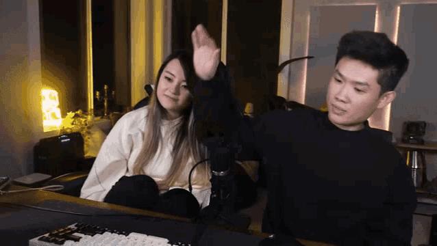 a man and a woman are sitting in front of a computer keyboard .