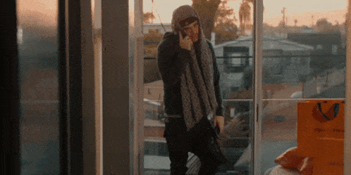 a man talking on a cell phone in front of a sliding glass door