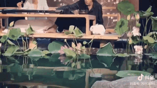 a white rabbit is sitting on a wooden table in front of a pond