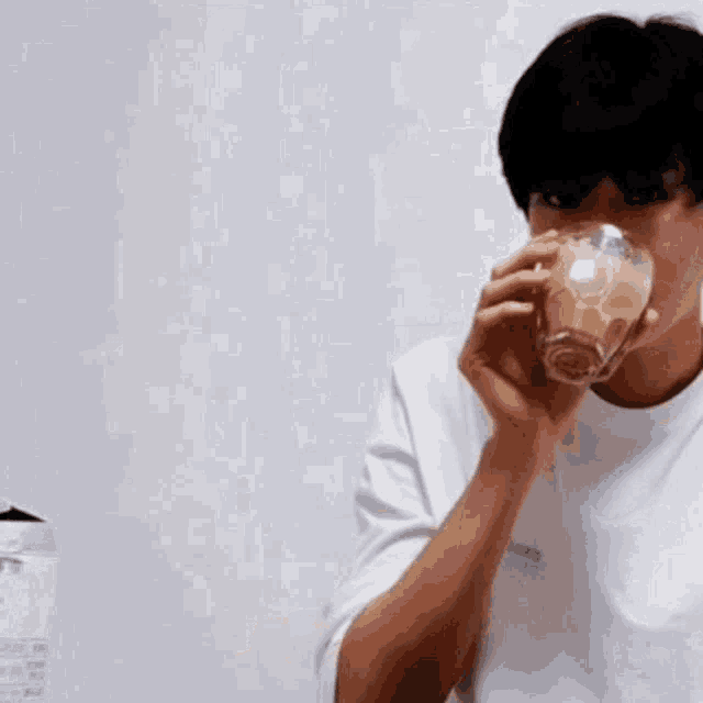 a man is drinking a glass of milk from a glass .