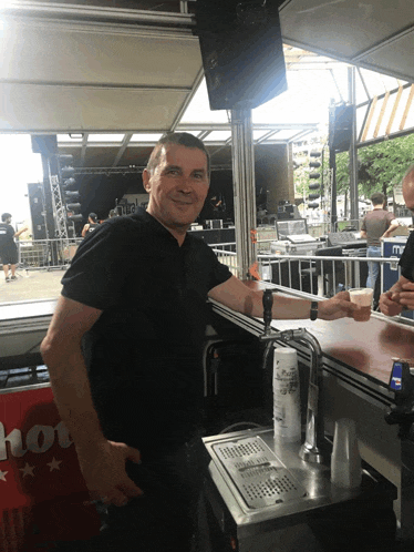 a man in a black shirt is standing in front of a machine that has a cup on it that says ' a '