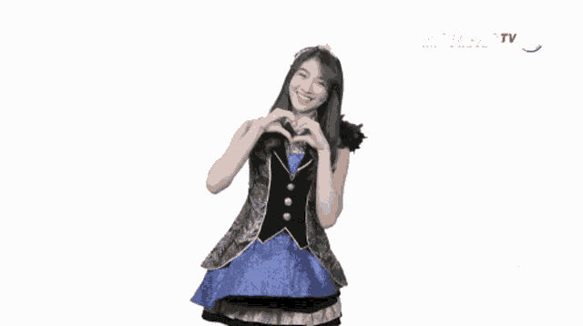 a woman in a blue dress making a heart with her hands in front of a kompas tv logo