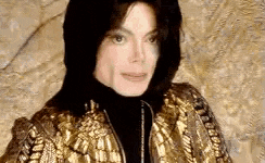 a close up of a man wearing a black turtleneck and a gold jacket with a hood .