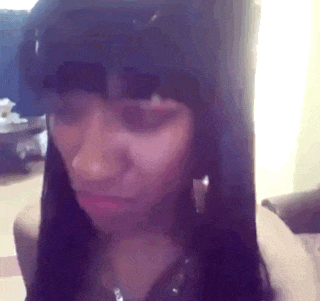 a woman with long black hair and bangs is making a funny face in a living room .