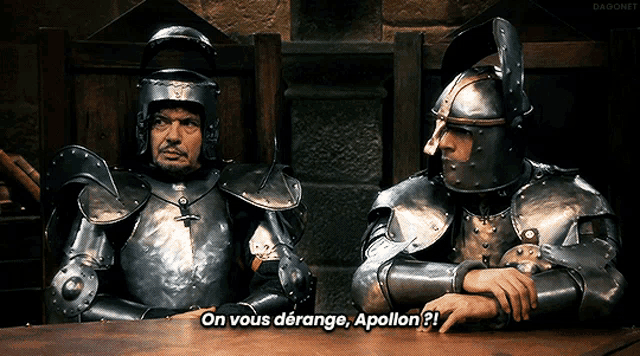 two men in armor are sitting at a table and one of them is saying on vous derange apollon