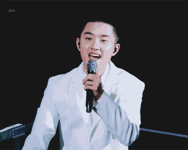 a man in a white jacket is holding a microphone in his hand