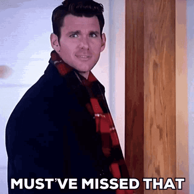 a man wearing a plaid scarf is standing in front of a door with the words must 've missed that written below him