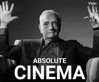 a man in a suit is sitting in a chair with his hands in the air and the words absolute cinema behind him