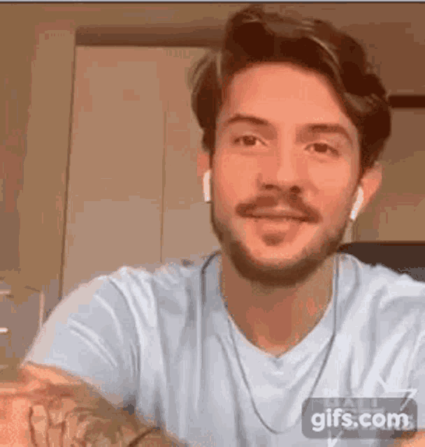 a man with a beard is wearing headphones and a blue shirt and smiling .