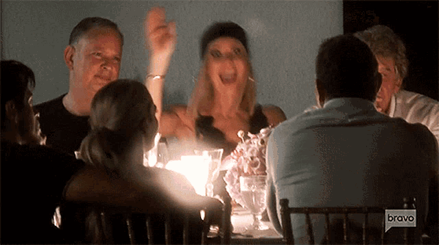 a group of people sitting at a table with a bravo logo on the bottom