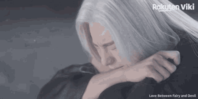 a man with long white hair is crying with the words love between fairy and devil above him
