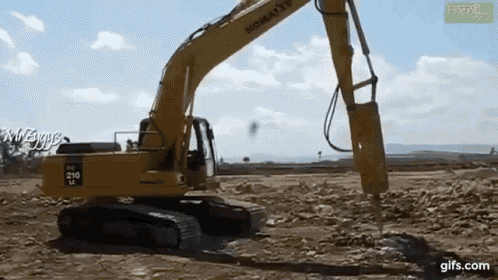 a yellow komatsu excavator is working in a dirt field .