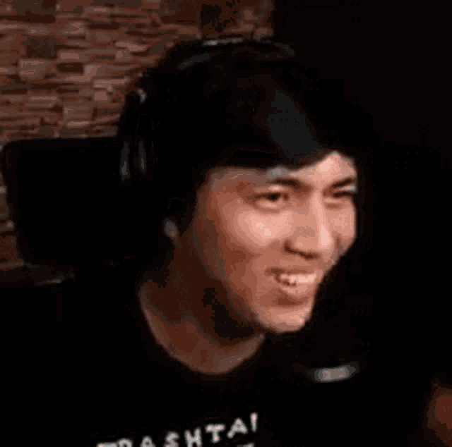 a man wearing headphones and a black shirt is laughing .