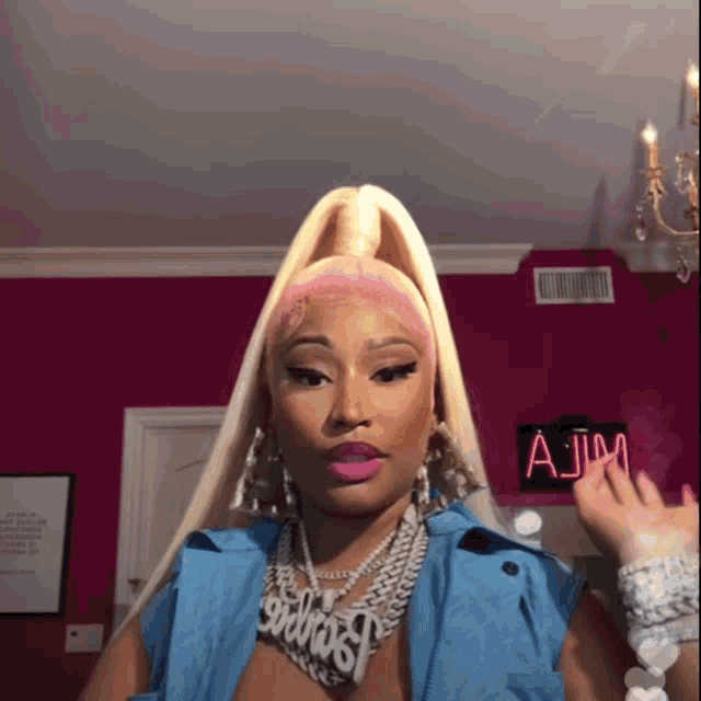a woman wearing a blue jacket and a necklace with the name nicki minaj on it