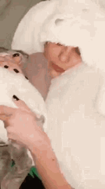 a woman wearing a white bunny hat is holding a white rabbit .