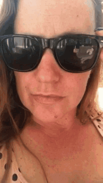 a close up of a woman wearing sunglasses making a funny face