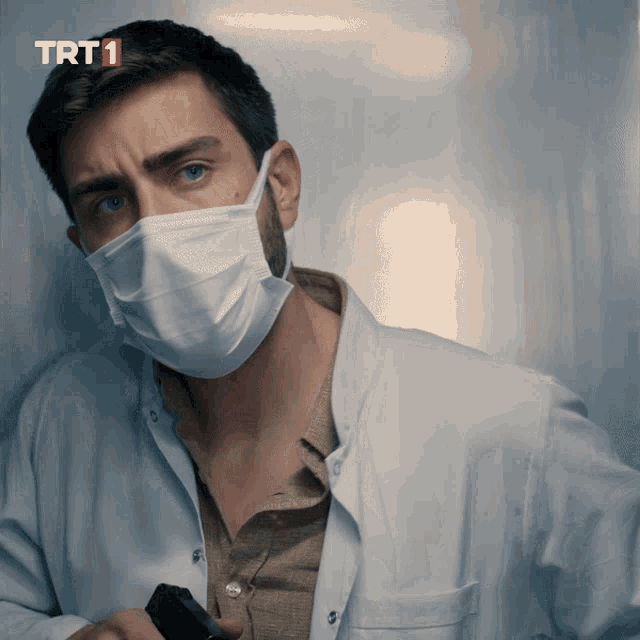 a man wearing a mask and a lab coat with trt1 written on the bottom