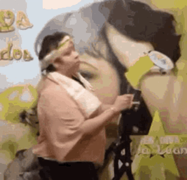 a woman with a towel around her neck is standing in front of a painting of a woman .