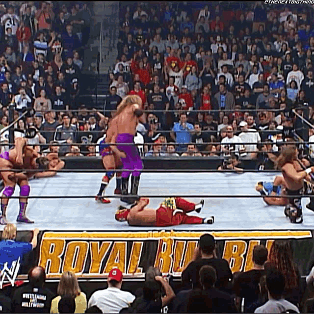 wrestlers in a ring with a sign that says royal rumble in the background